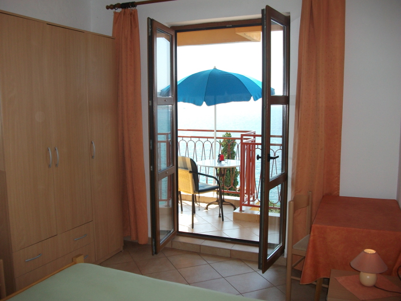 Schlafzimmer mit einem großen Französischen Bett und einem Einzelbett sowie einem Balkon und Meerblick.